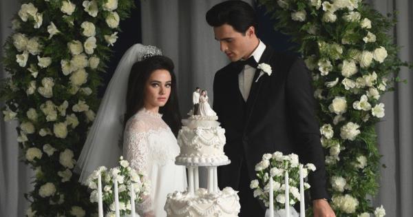 Elvis and Priscilla getting married wearing a tuxedo and wedding dress with their cake in front of them in Priscilla.