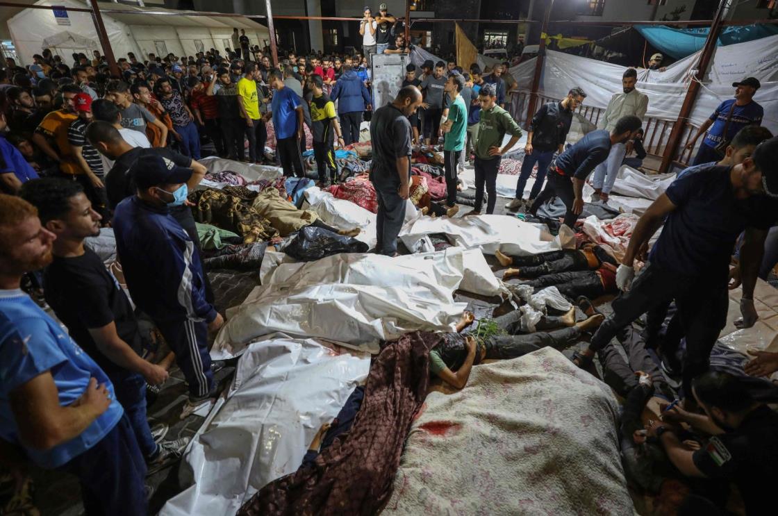 People gather around the bodies of Palestinians killed after a strike ripped through the Ahli Arab Hospital in central Gaza after they were transported to Al-Shifa Hospital, on Oct. 17, 2023. (AFP Photo)